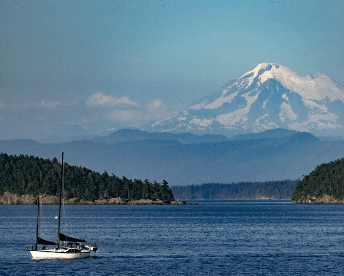 Sailboat on ocean with snowy mountain background.
