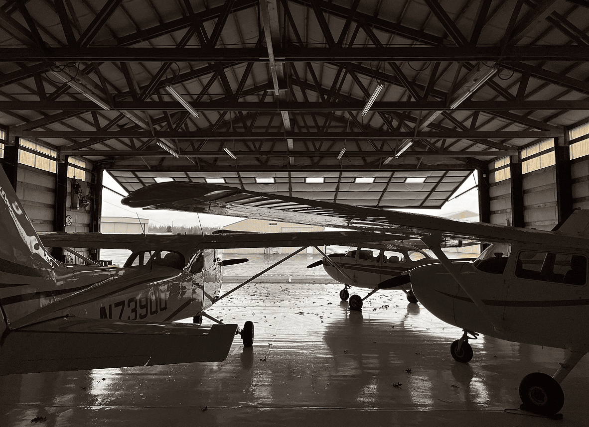 Small airplanes parked inside an open hangar.