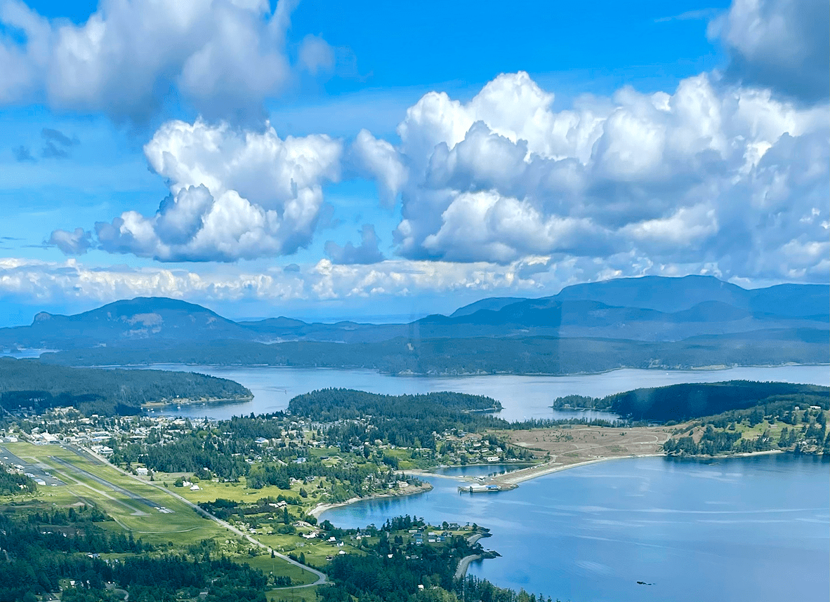 Coastal landscape with clouds and mountains.