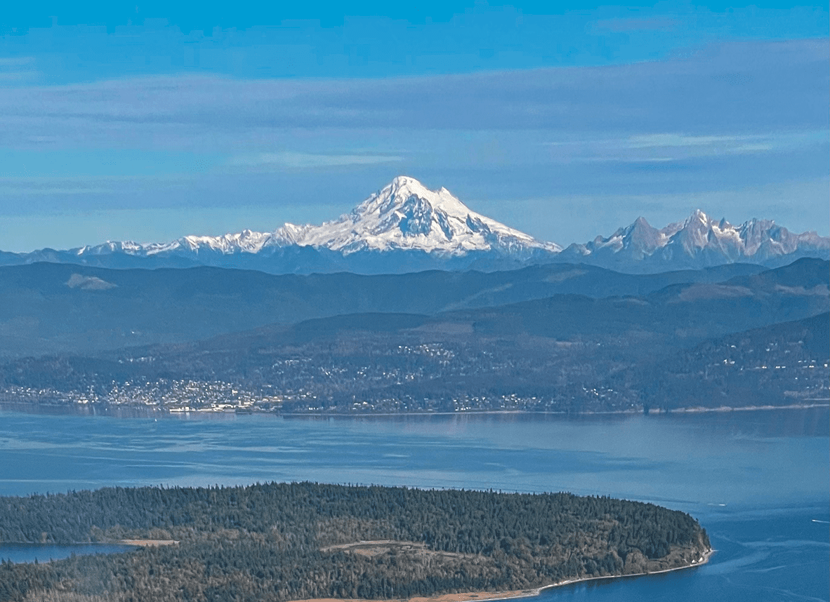 Snow-capped mountain with lake and forest island.