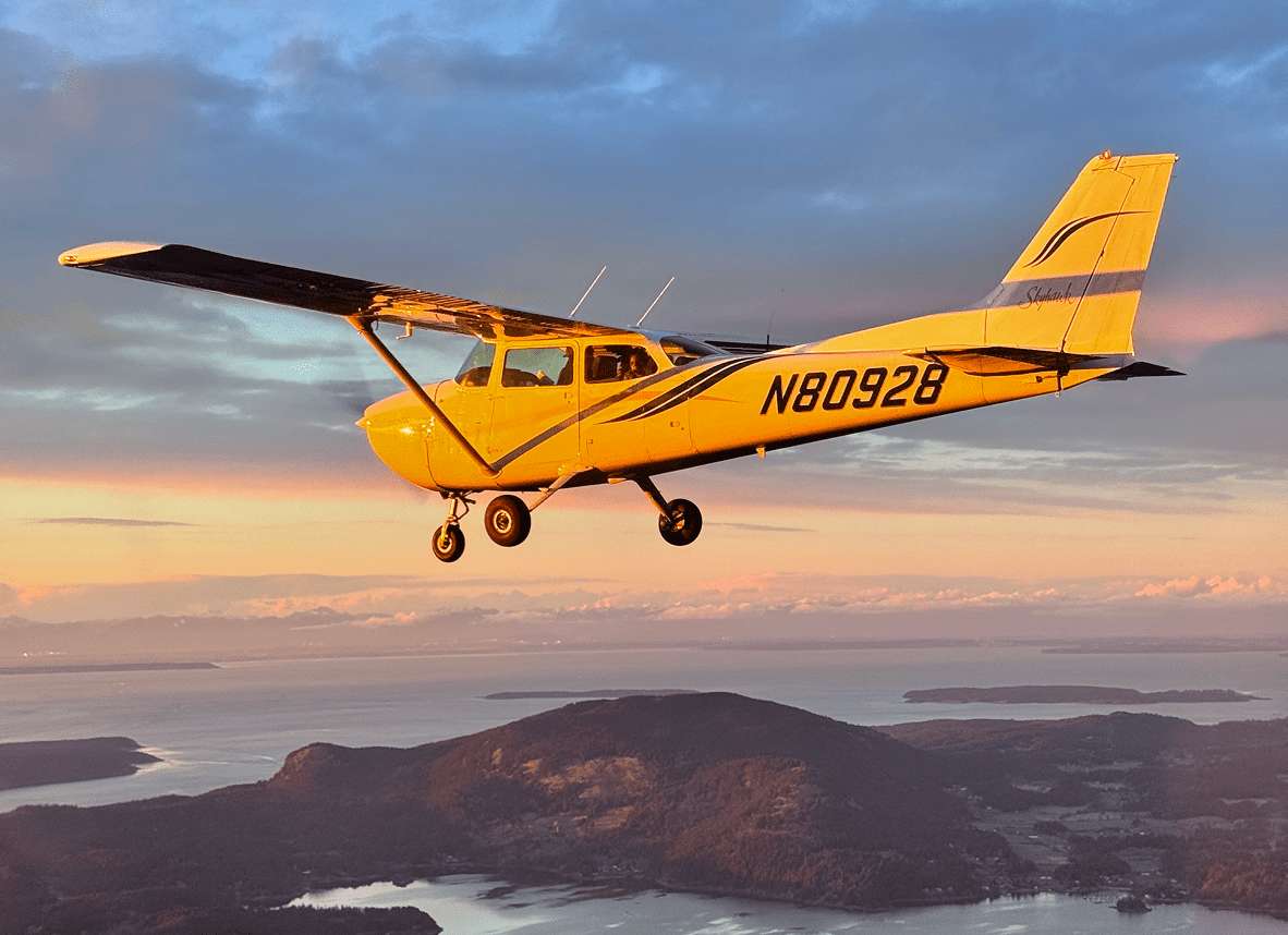 Yellow airplane flying over scenic landscape.