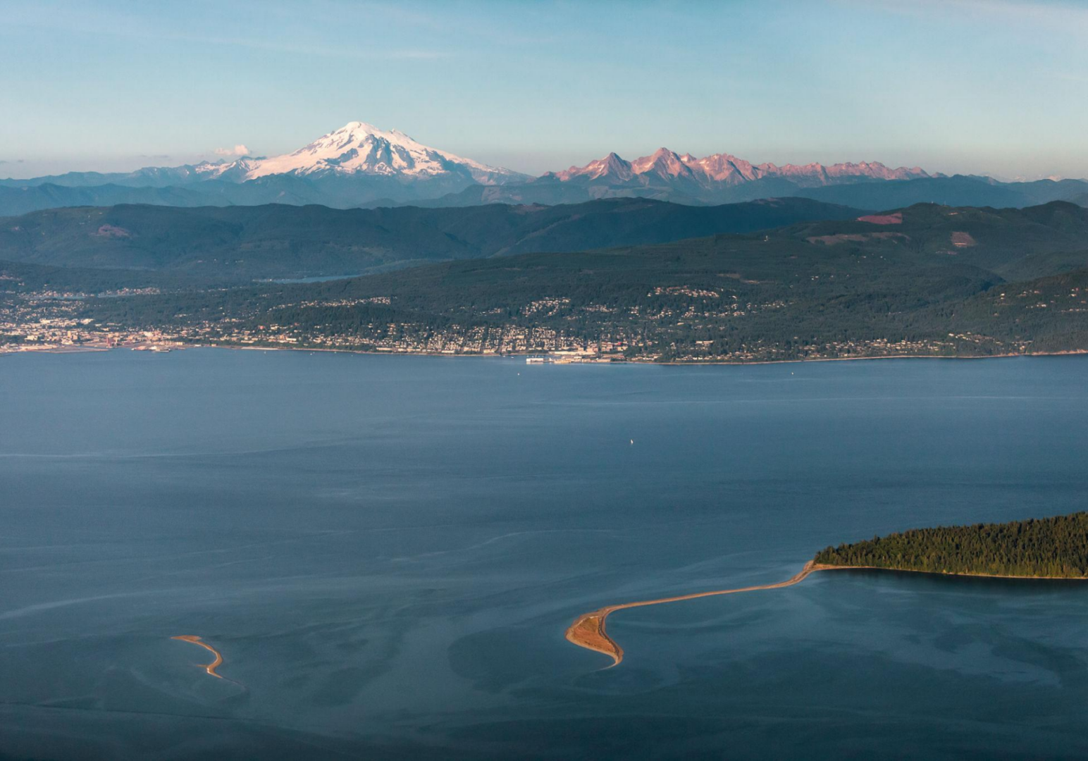 Snow-capped mountain with lake and peninsula.