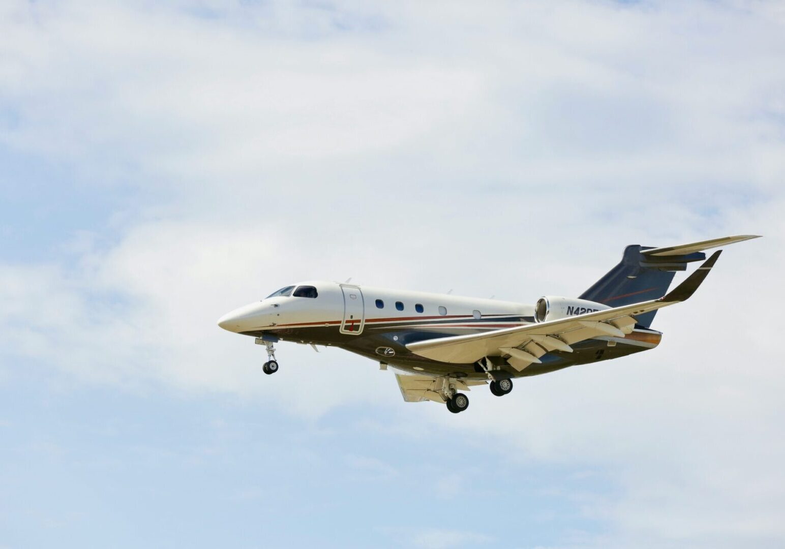 Private jet landing under cloudy blue sky