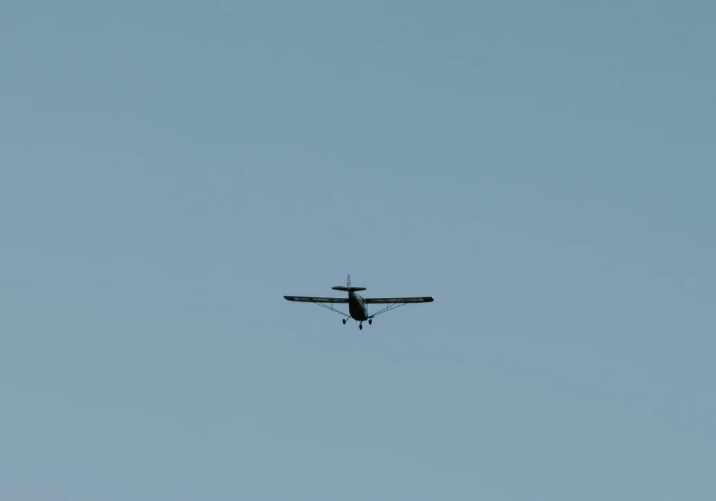 Small airplane flying in clear blue sky.